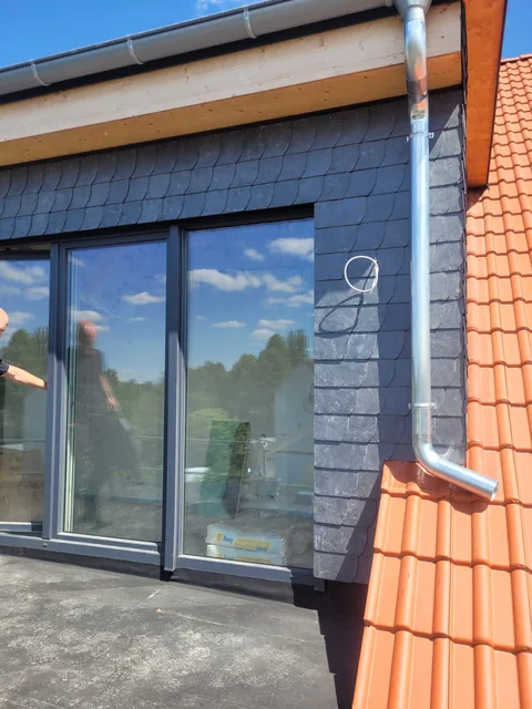 Fensterfront mit dunkler Verkleidung und Dachüberstand