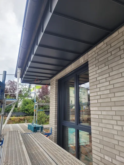 Dachüberstand mit Metallverkleidung über einer Fensterfront