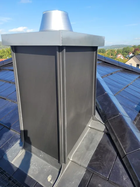 Schornstein mit dunkler Metallverkleidung und Abdeckung