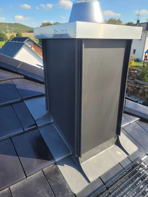 Metallverkleidung eines Schornsteins auf einem dunkel eingedeckten Dach