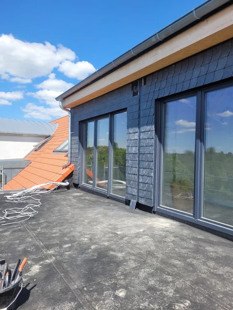 Fensterfront mit dunkler Verkleidung an einer Dachfläche